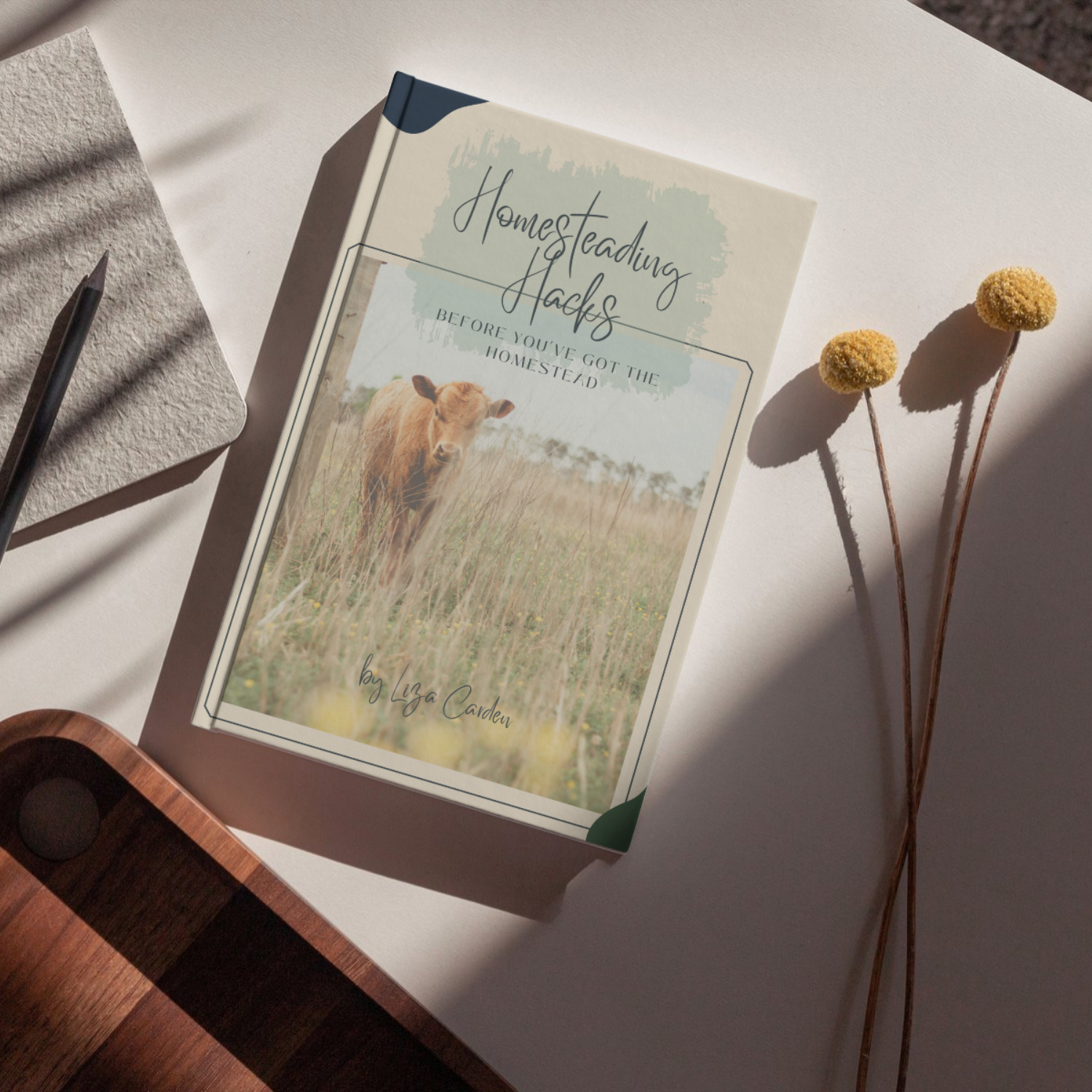 book with cover of cow in field is sitting on a table with simple flowers